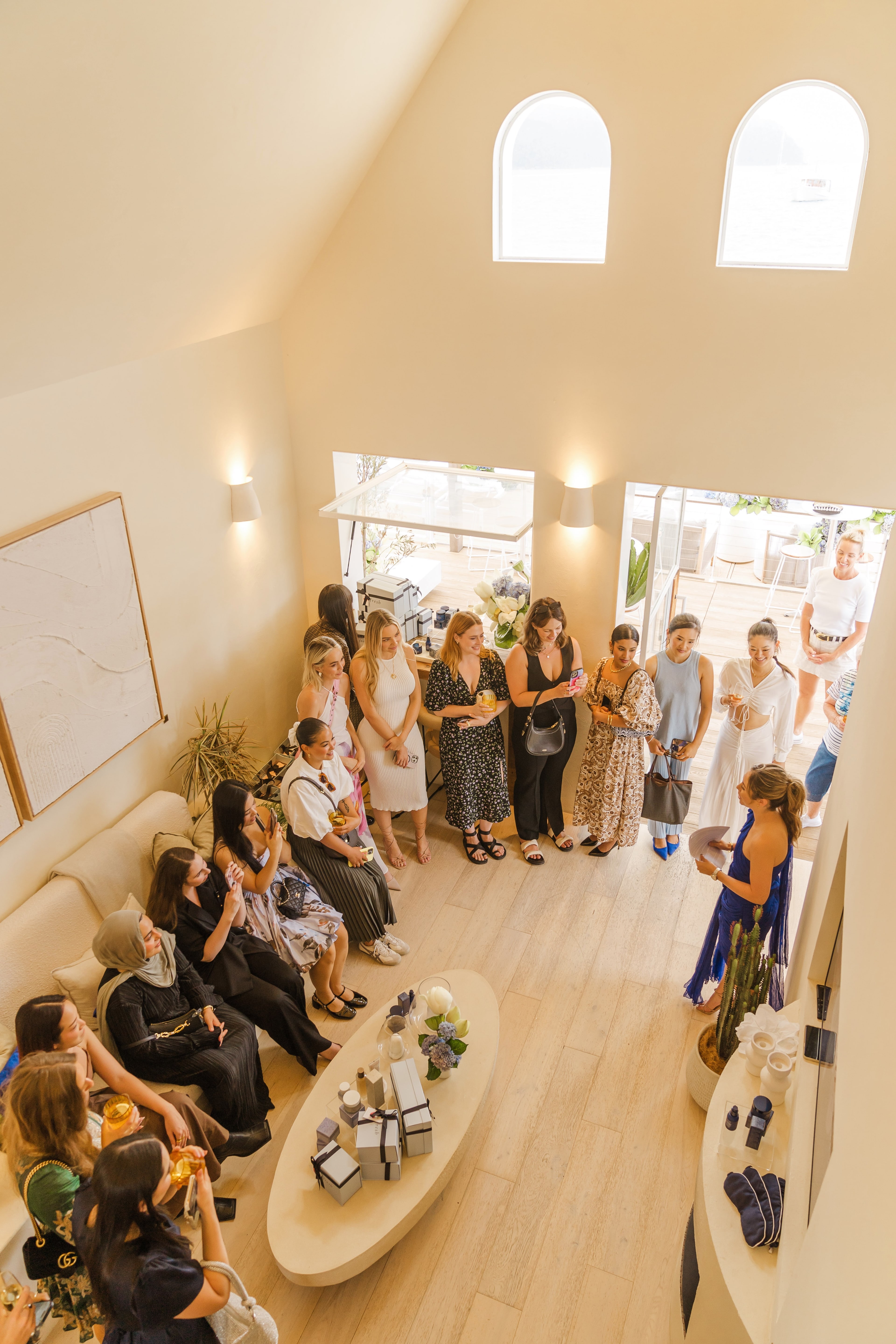 Overhead view of guests gathered in the light-filled pavilion for a Fresh presentation, with product displays on round tables.
