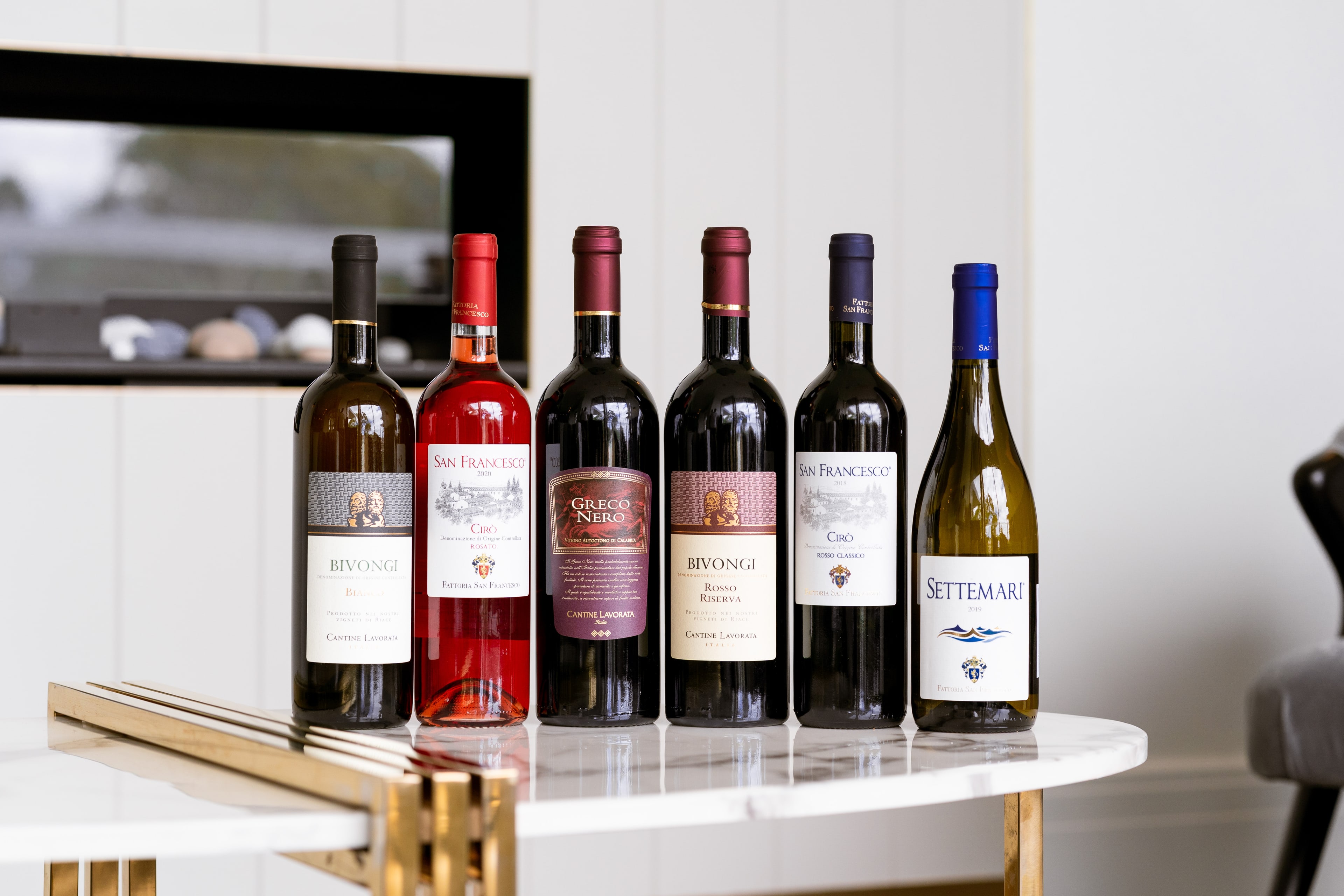 Six Italian wine bottles, including Bivongi and Settemari, arranged on a marble bar cart in a bright modern interior.