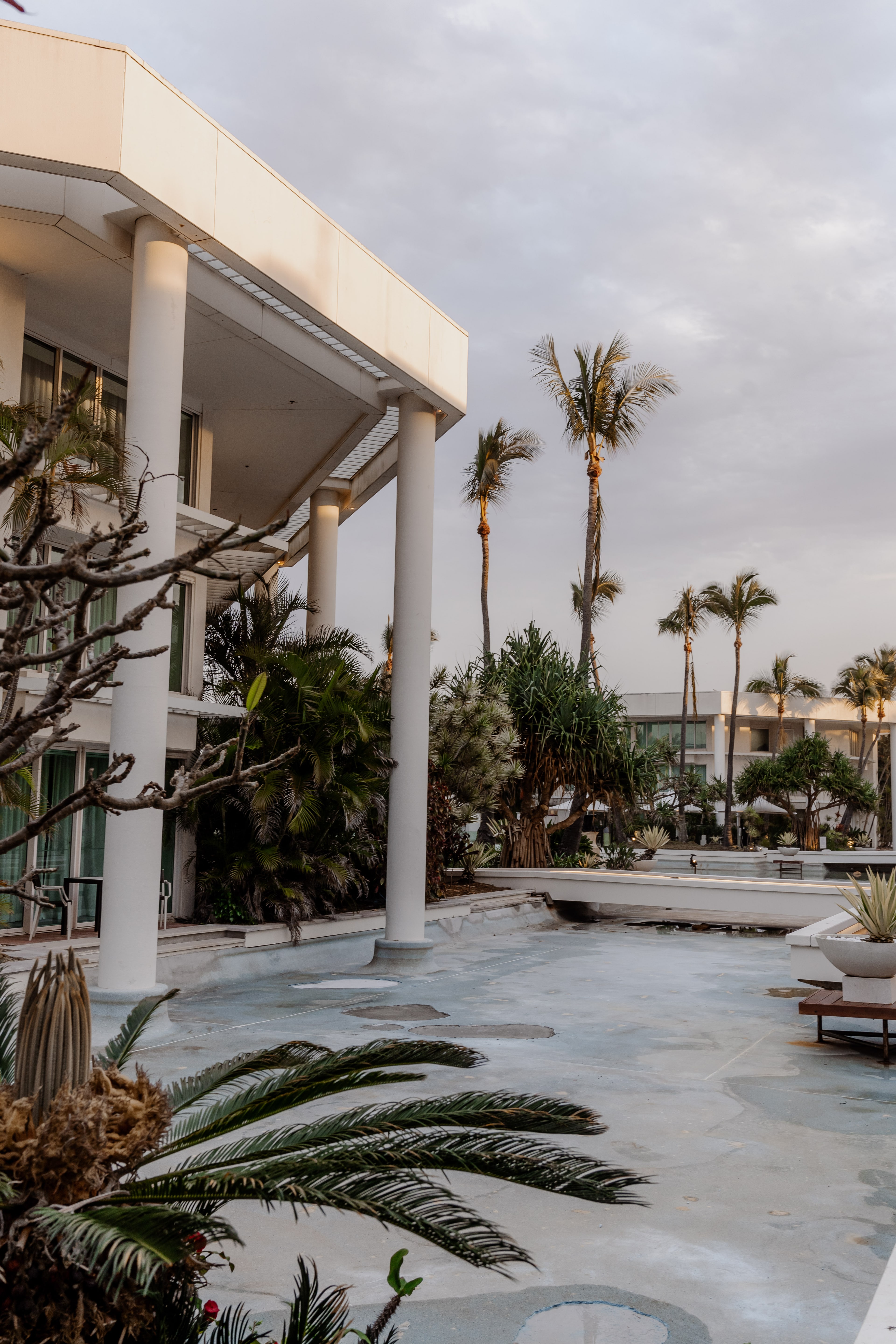 Sheraton Grand Mirage resort exterior at dusk, with white columns, palm trees and tropical landscaping beside a pool terrace.
